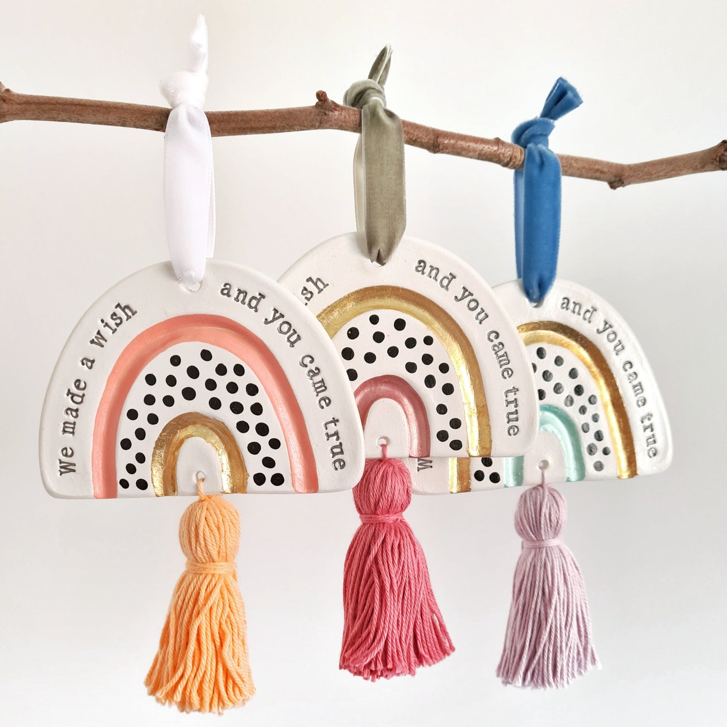 Three rainbows that say 'We made a wish and you came true'. Hung with velvet ribbon, featuring a gold leaf arch and a tassel. 